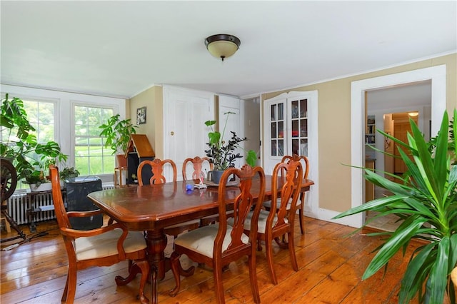 dining space with radiator, crown molding, and hardwood / wood-style flooring