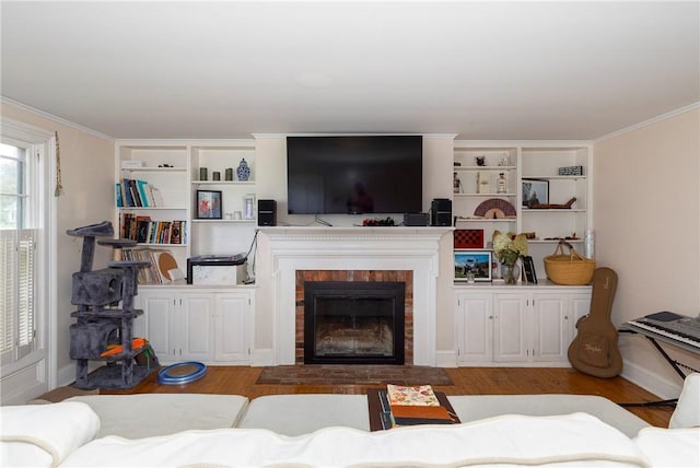 living room with wood-type flooring, crown molding, and a brick fireplace