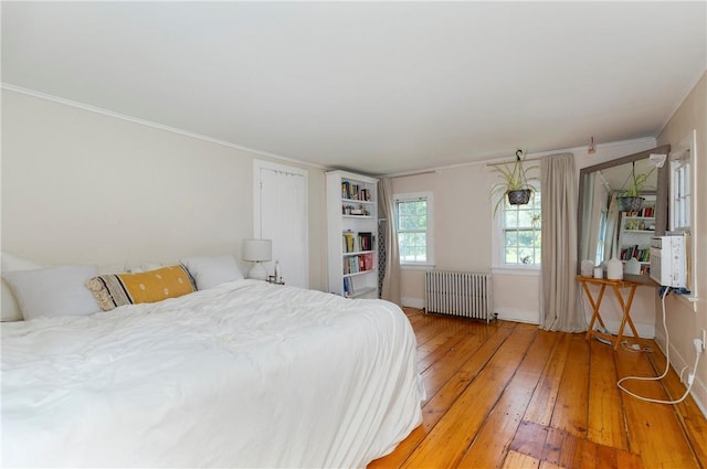 bedroom with hardwood / wood-style flooring, radiator, and ornamental molding