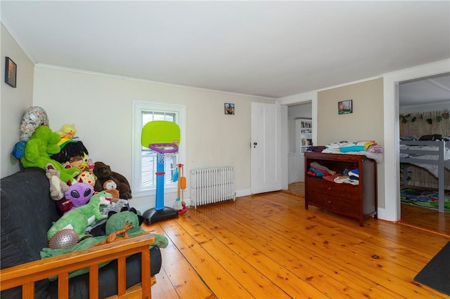 interior space with radiator heating unit, crown molding, and wood-type flooring