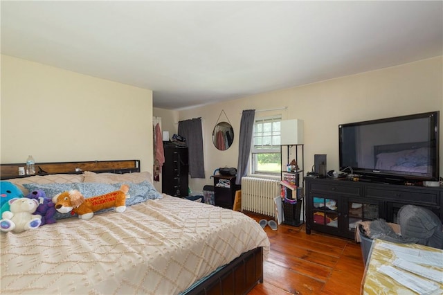 bedroom featuring radiator heating unit and hardwood / wood-style flooring