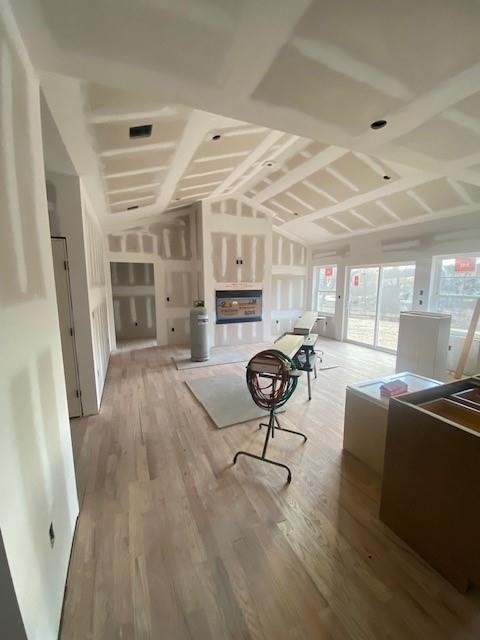 unfurnished living room with light wood-type flooring and vaulted ceiling