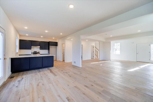 kitchen with stainless steel range oven, kitchen peninsula, and light hardwood / wood-style flooring