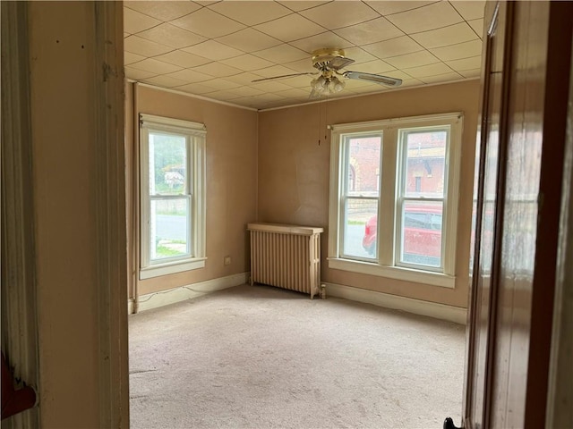 unfurnished room featuring ceiling fan, light carpet, and radiator