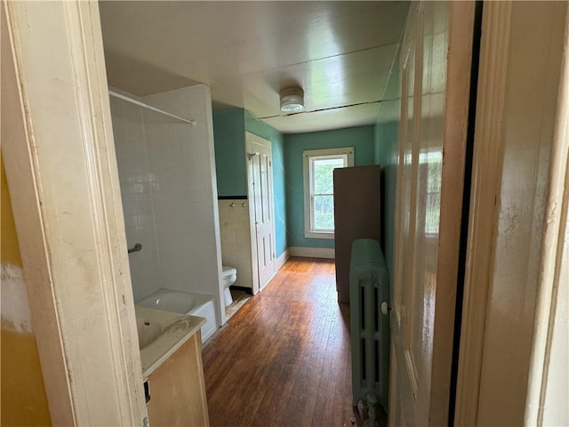 bathroom with toilet, radiator heating unit, shower / washtub combination, and hardwood / wood-style flooring