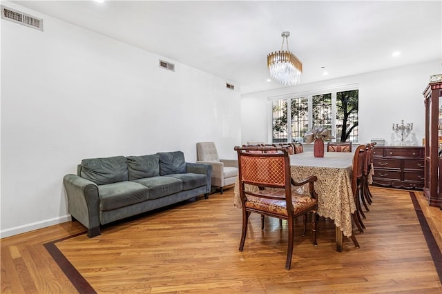 dining space featuring light wood-type flooring and an inviting chandelier