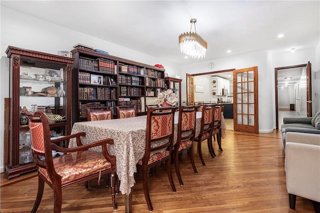 dining space with hardwood / wood-style floors, a chandelier, and french doors