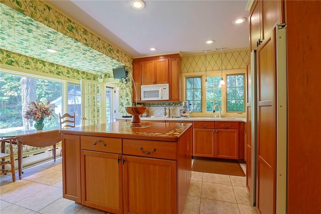 kitchen with decorative backsplash, sink, pendant lighting, light tile patterned floors, and a kitchen island