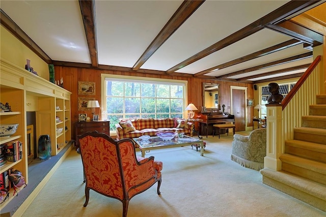 carpeted living room with beamed ceiling and wood walls