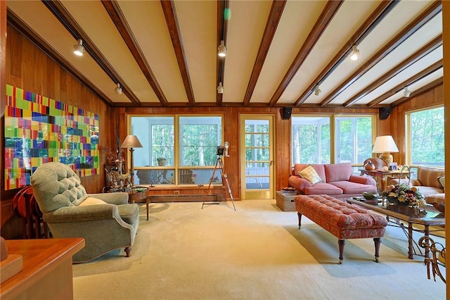 carpeted living room featuring vaulted ceiling with beams, wood walls, plenty of natural light, and a baseboard radiator