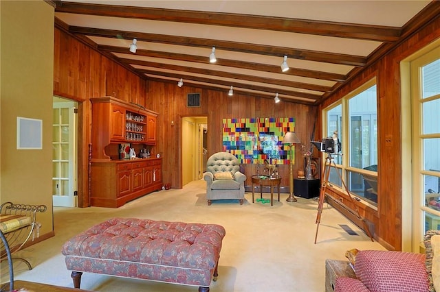 carpeted living room featuring vaulted ceiling with beams, wooden walls, and indoor bar