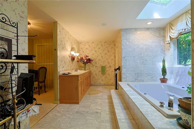 bathroom with vanity, tiled tub, and a skylight