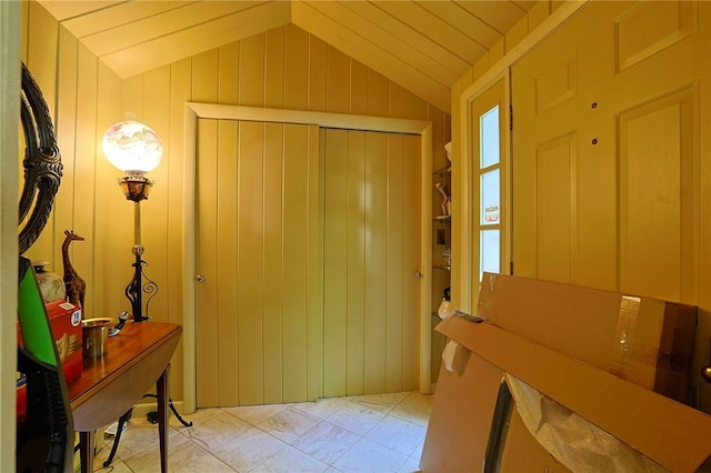 foyer featuring wooden walls and lofted ceiling