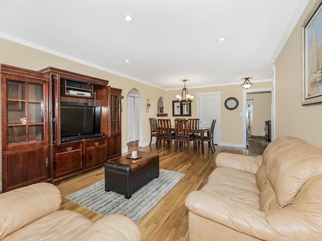 living room featuring light hardwood / wood-style floors, ornamental molding, and an inviting chandelier