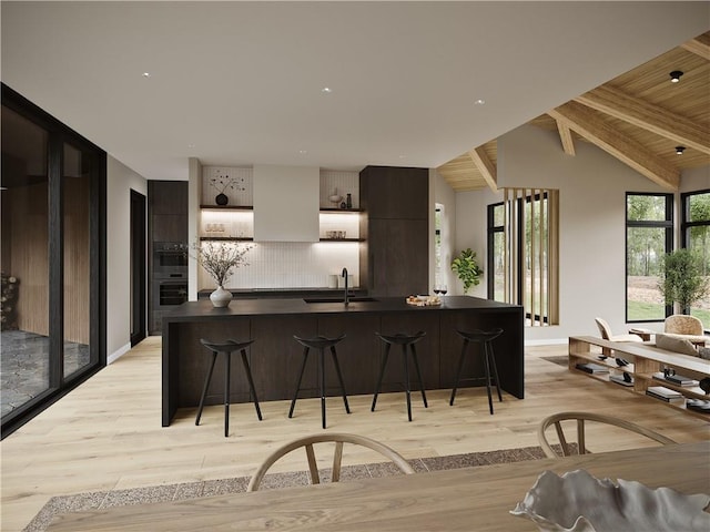 kitchen with lofted ceiling with beams, light hardwood / wood-style flooring, a breakfast bar area, and sink