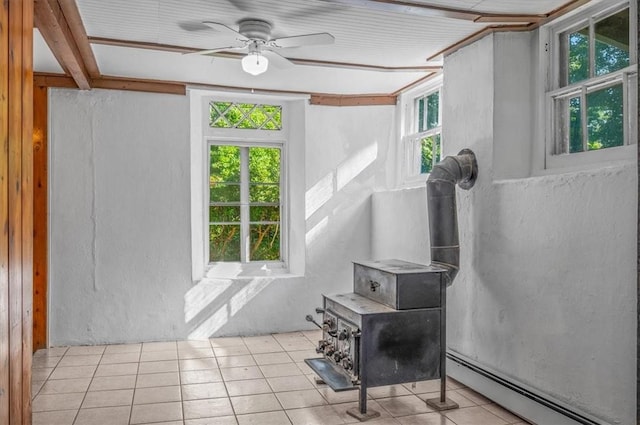 tiled living room with plenty of natural light, ceiling fan, a wood stove, and a baseboard radiator