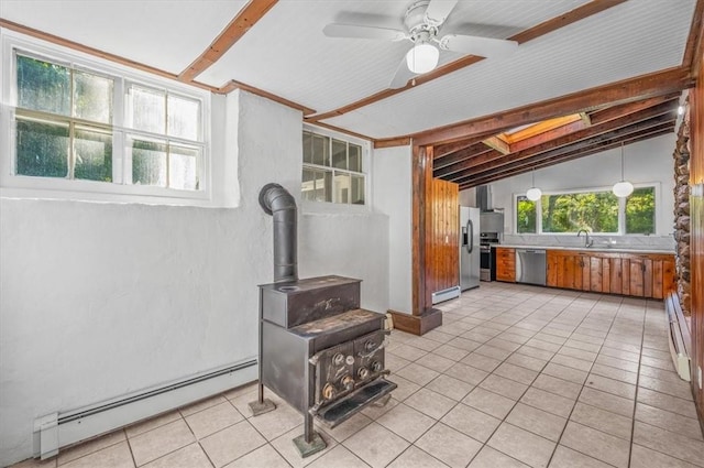 kitchen with a wood stove, a baseboard heating unit, vaulted ceiling, ceiling fan, and appliances with stainless steel finishes