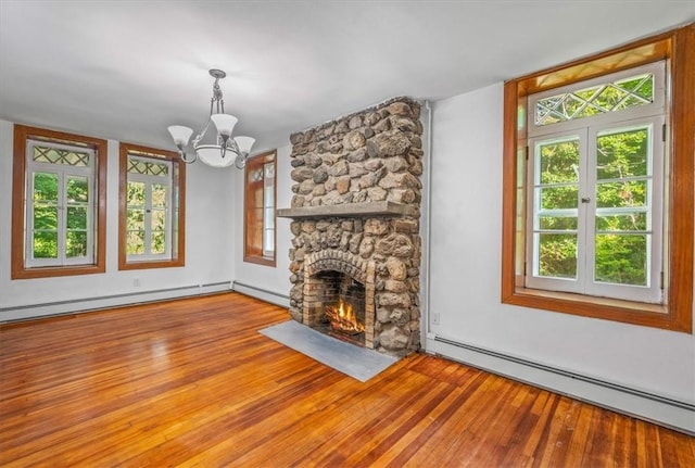 unfurnished living room featuring light wood-type flooring, a stone fireplace, a baseboard heating unit, and a notable chandelier