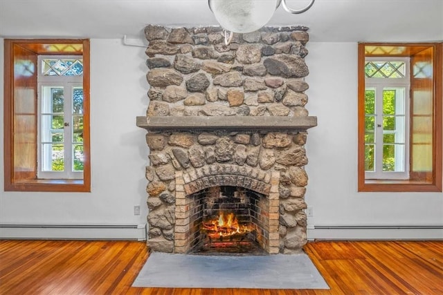 room details with a stone fireplace, wood-type flooring, and a baseboard heating unit