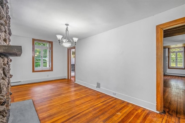 interior space featuring a baseboard heating unit, wood-type flooring, a wealth of natural light, and a chandelier