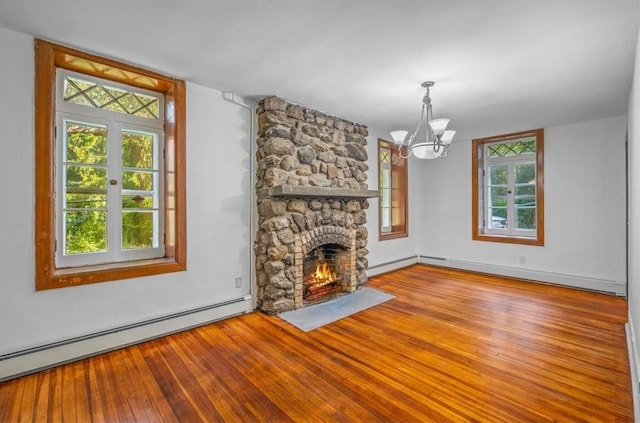 unfurnished living room featuring a wealth of natural light, a fireplace, a chandelier, and a baseboard heating unit