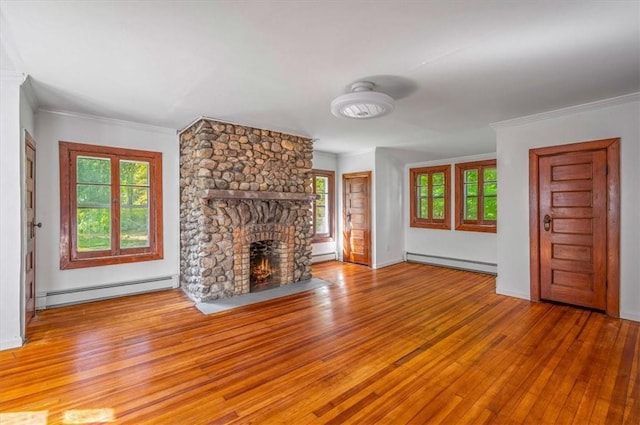 unfurnished living room with baseboard heating, a fireplace, light hardwood / wood-style flooring, and ornamental molding