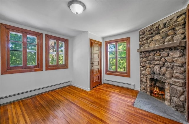 unfurnished living room featuring a fireplace, light hardwood / wood-style floors, and a baseboard heating unit