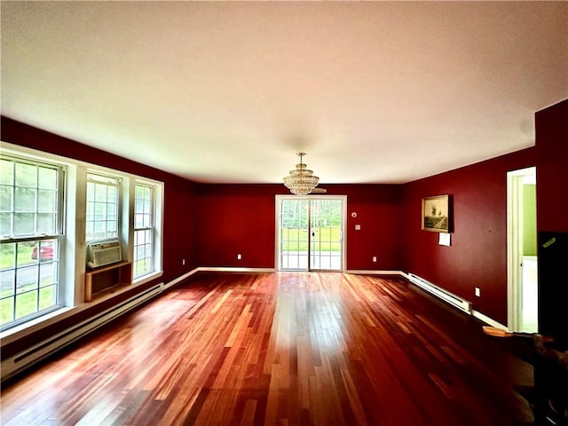 unfurnished room with baseboard heating, a notable chandelier, and hardwood / wood-style flooring