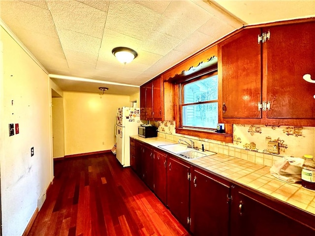 kitchen with tile countertops, white refrigerator, dark hardwood / wood-style floors, and sink