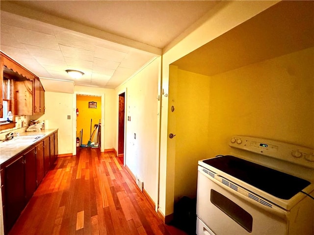 kitchen featuring hardwood / wood-style flooring, white electric range oven, and sink