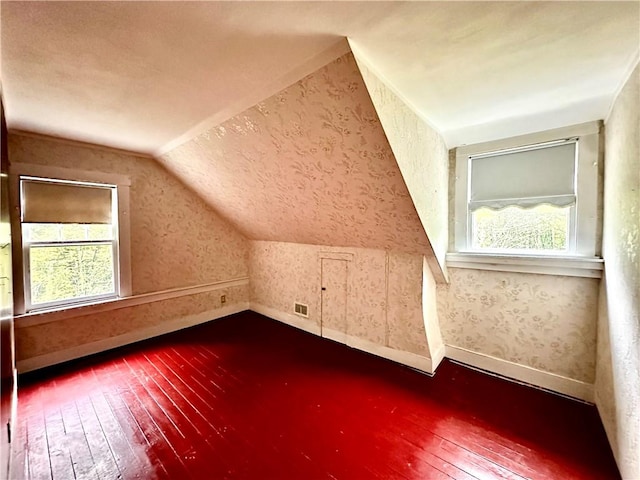 additional living space with a healthy amount of sunlight, wood-type flooring, and vaulted ceiling