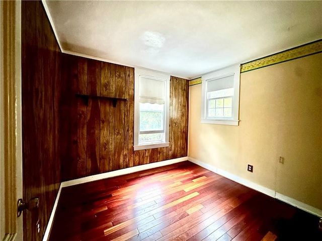 spare room with hardwood / wood-style flooring and wooden walls