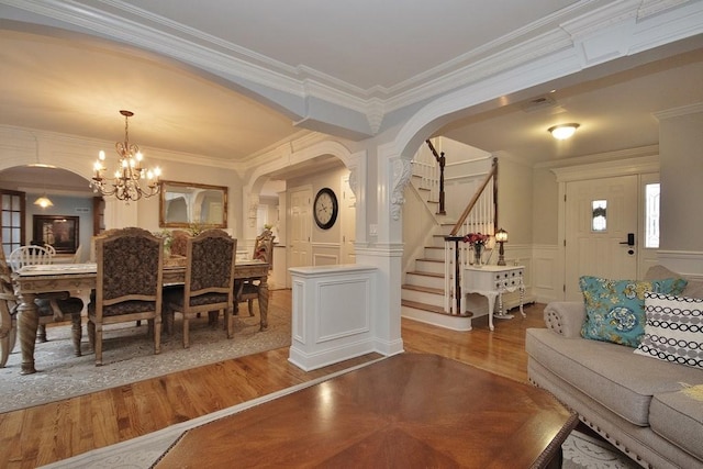 dining space featuring wood-type flooring, ornamental molding, and a chandelier