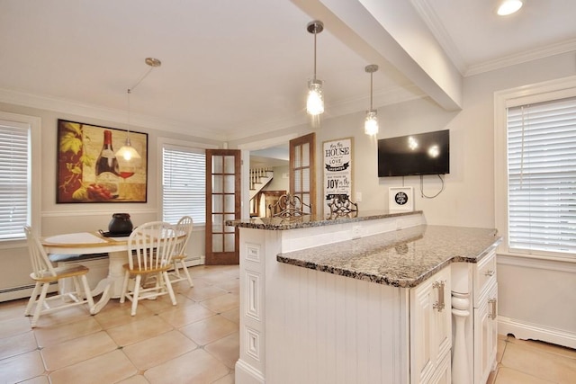 kitchen featuring kitchen peninsula, ornamental molding, dark stone counters, light tile patterned floors, and hanging light fixtures