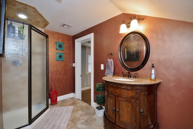 bathroom featuring a shower with door, vanity, vaulted ceiling, and tile patterned flooring