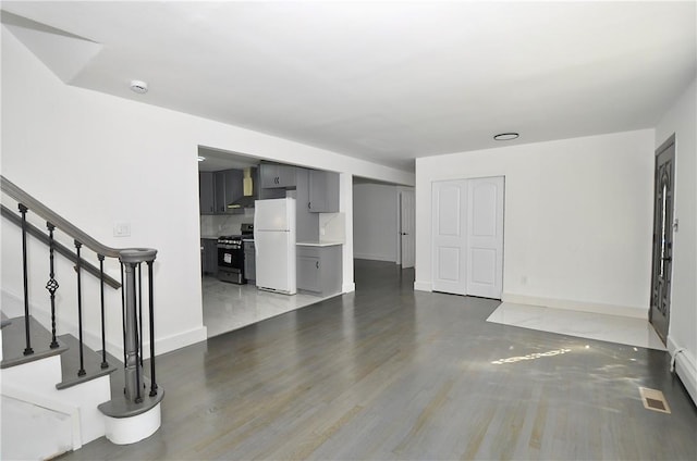 unfurnished living room with wood-type flooring and a baseboard heating unit