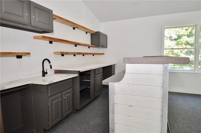 kitchen with gray cabinetry, sink, dark carpet, and lofted ceiling