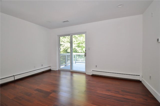 spare room with dark wood-type flooring and a baseboard heating unit