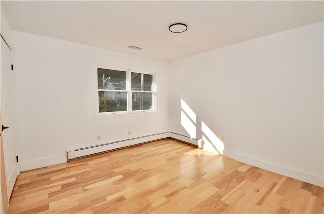 unfurnished room featuring baseboard heating and light hardwood / wood-style flooring