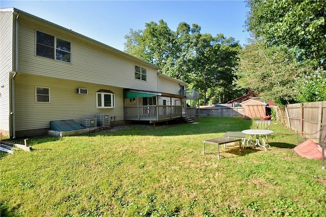 rear view of house featuring a storage unit, a wall unit AC, a lawn, and a wooden deck