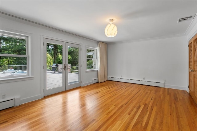 interior space with a healthy amount of sunlight, light wood-type flooring, and a baseboard heating unit