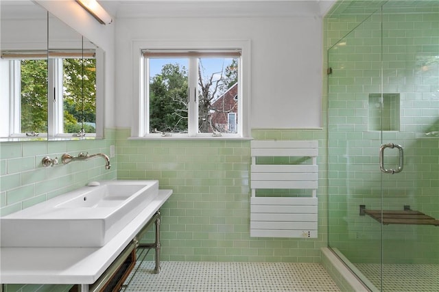 bathroom featuring tile patterned flooring, a shower with door, tile walls, and sink