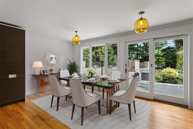 dining area with light wood-style floors and ornamental molding