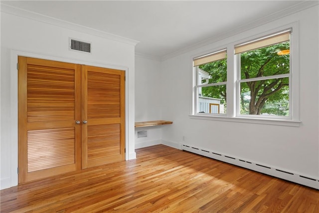 spare room with visible vents, crown molding, a baseboard heating unit, and light wood-type flooring