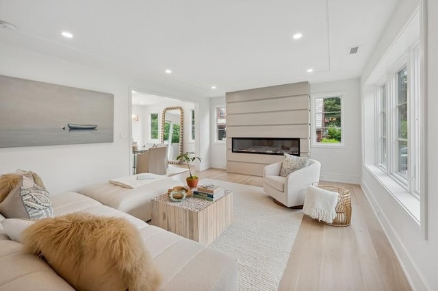 living room with a large fireplace and light hardwood / wood-style floors