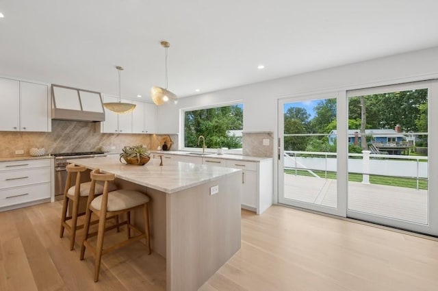 kitchen featuring premium range hood, a center island, decorative light fixtures, high end stainless steel range oven, and white cabinetry