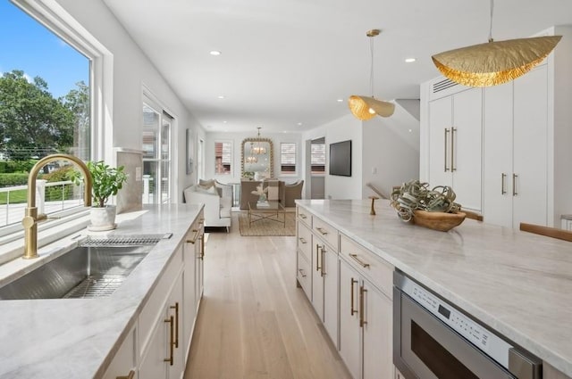 kitchen featuring sink, light stone countertops, decorative light fixtures, and white cabinetry