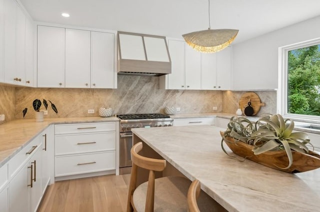 kitchen featuring high end stainless steel range, white cabinets, and decorative light fixtures