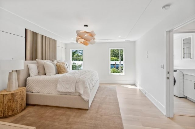 bedroom with washer / dryer and light hardwood / wood-style floors