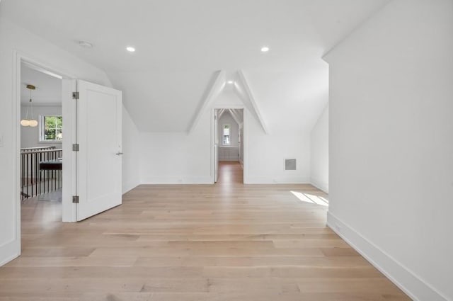 bonus room with light wood-type flooring and vaulted ceiling